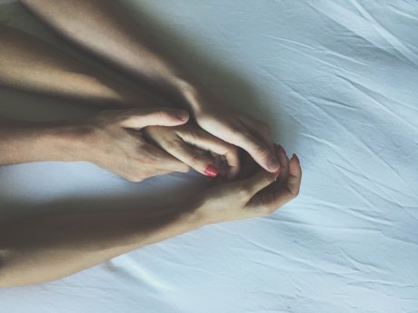 ruke žene i muškarca na krevetu