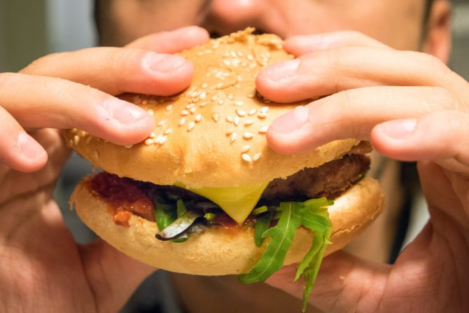 čovek jede hamburger