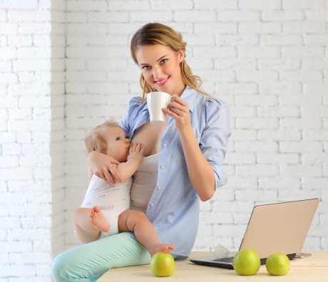 mama pije čaj i drži bebu